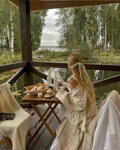 a woman sitting on a porch next to a table filled with pastries and drinks