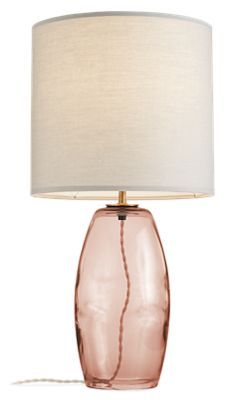 a pink glass table lamp with a white shade on the base and a light bulb plugged in