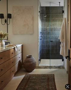 a bathroom with a shower, sink and rug on the floor in front of it