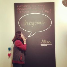 a woman standing in front of a chalkboard with an empty speech bubble on it