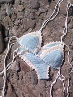 a crocheted bathing suit is laying on some rocks