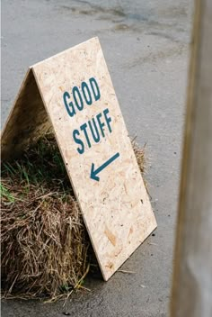 there is a sign that says good stuff in front of a pile of hay and grass