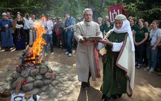 two people standing next to each other near a fire