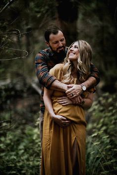 a man and woman hugging in the woods