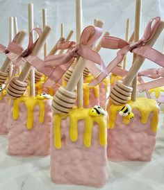 there are some candy pops with yellow icing on them and pink sticks sticking out of them