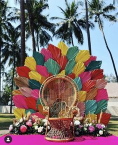 a colorful display with umbrellas and flowers on the ground in front of palm trees