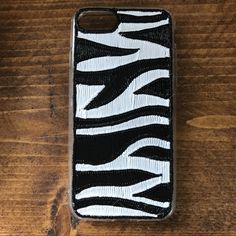 a black and white zebra print phone case sitting on top of a wooden table