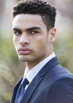 a close up of a person wearing a suit and tie with a serious look on his face