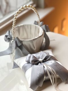 a basket with pearls and ribbon tied around it sitting on a table next to other items