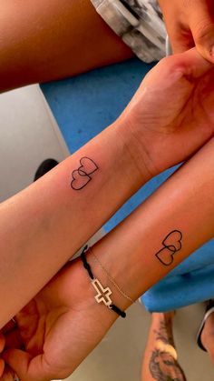 two people holding hands with tattoos on their arms and wrist, one has a cross in the middle