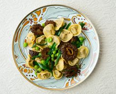 a plate filled with dumplings and peas on top of a white tablecloth next to a napkin