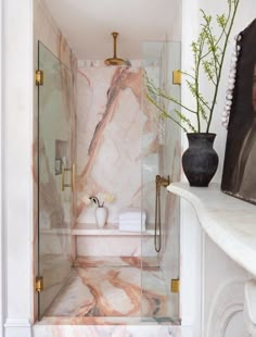 a bathroom with marble walls and flooring next to a white shelf filled with flowers