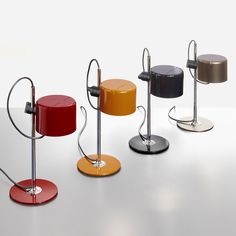 four different colored stools are standing on a table with one chair in the middle