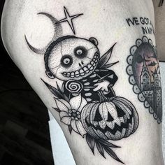 a woman's thigh with a tattoo on it and a skeleton holding a pumpkin