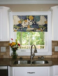 a kitchen sink under a window with flowers on it