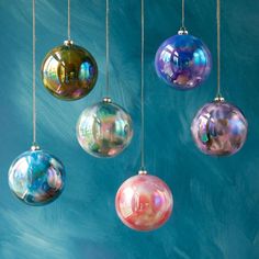 five glass ornaments hanging from strings against a blue background