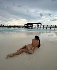 a woman is laying on the sand at the beach