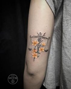 a woman's arm with an orange flower and scale tattoo on her left arm