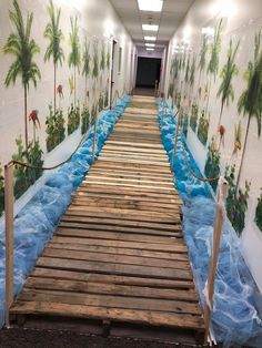 a long wooden walkway that is painted with blue water and palm trees on the wall