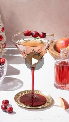 a glass filled with liquid sitting on top of a table next to apples and cranberries