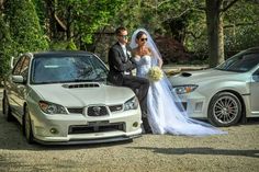 a bride and groom standing next to their cars