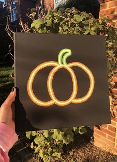 a person holding up a sign with two pumpkins on it