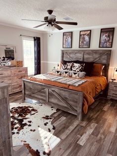 a bedroom with a bed, dressers and pictures on the wall