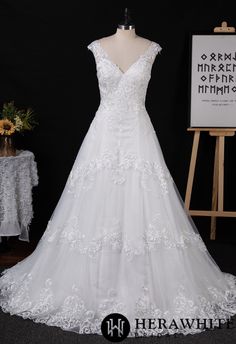 a white wedding dress is on display in front of a black backdrop with an easel