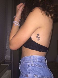 a woman with a flower tattoo on her left side shoulder and right arm behind her back