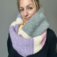 a woman wearing a multicolored knitted cowl with a scarf around her neck