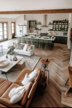 a living room filled with furniture next to a kitchen and dining room table on top of a hard wood floor