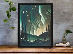 an art print of the aurora bore is displayed on a shelf next to a potted plant