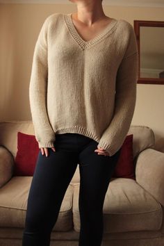 a woman standing in front of a couch with her hands on her hips