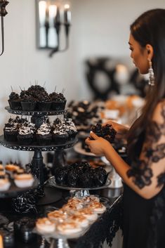 a woman standing in front of a table filled with cupcakes and pastries