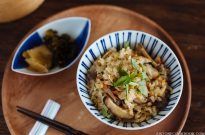 two bowls filled with rice and vegetables next to chopsticks on a wooden tray