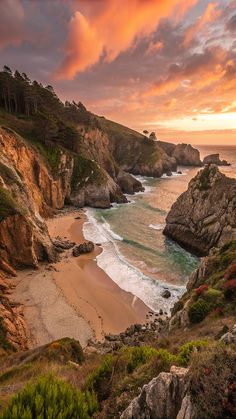 the sun is setting over an ocean and rocky coastline