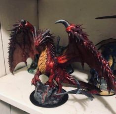 two red dragon figurines sitting on top of a white shelf