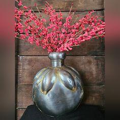 a metal vase with red flowers in it