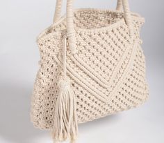 a crocheted bag with tassels on the handles and handle is shown against a white background