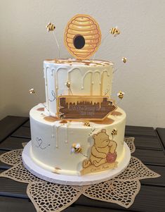 a winnie the pooh birthday cake with honeycombs and bees on top is sitting on a doily