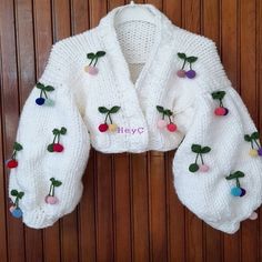 a white knitted sweater with cherries and pom - poms on it