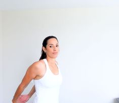 a woman standing in front of a white wall with her hands on her hips and looking at the camera