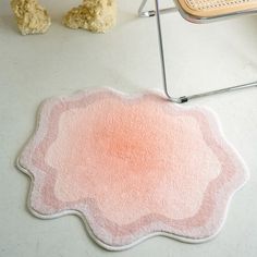 a pink rug sitting on top of a white floor next to a chair and teddy bear