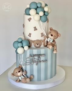 a three tiered blue and white cake with teddy bears on the top, balloons in the air