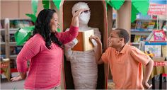 a woman standing next to a man in front of a cardboard mannequin holding a box