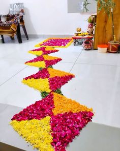 a long row of flowers on the ground in front of a wall with other decorations