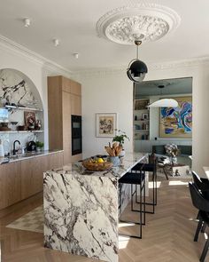 a large kitchen with marble counter tops and wooden cabinets in the center, along with black chairs