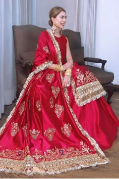 a woman in a red dress sitting on a couch wearing a gold and red outfit