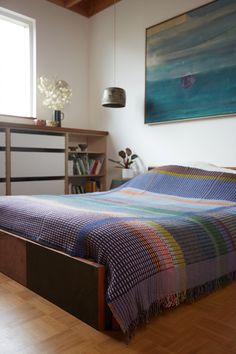 a bed sitting in a bedroom next to a dresser and book shelf on top of a hard wood floor