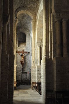 an empty church with a crucifix on the wall and stone flooring